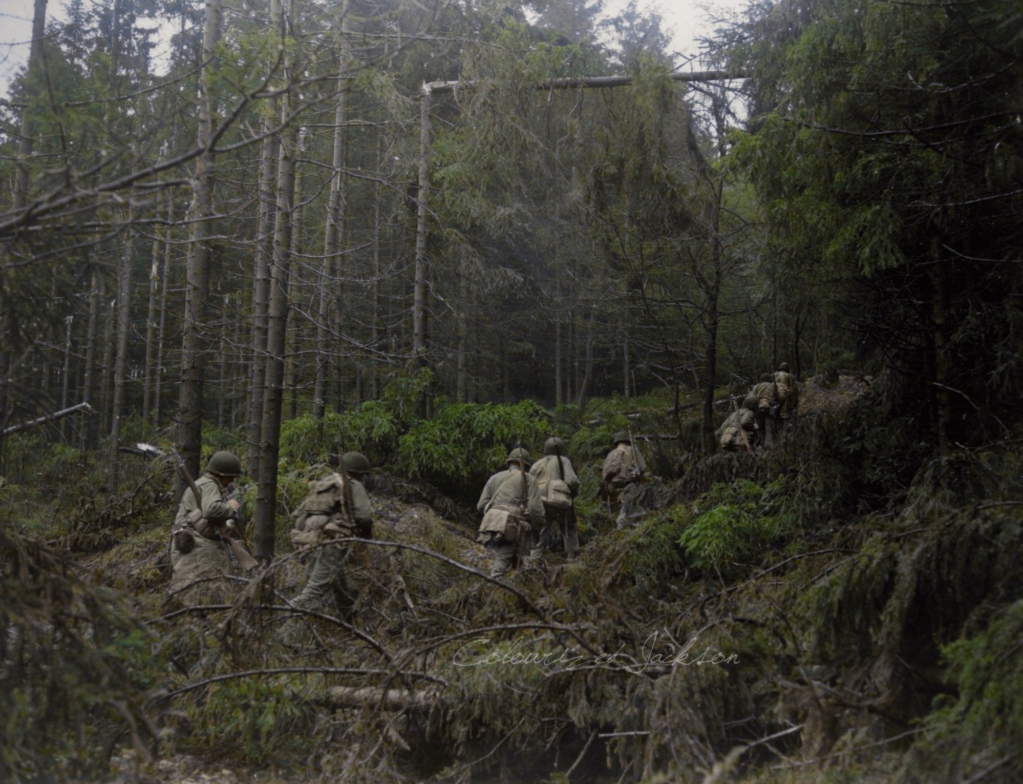 First U.S. Army infantrymen start through heavy woods on way to attack German-held barracks near Siegen, Germany